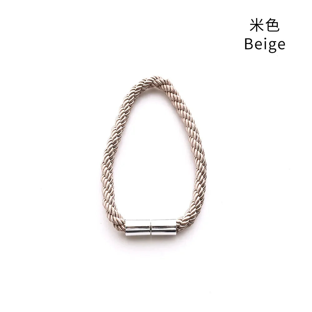 A close-up of a beige rope bracelet with a silver magnetic clasp.