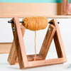 A wooden yarn ball holder with a stable base displaying a skein of golden yellow yarn.