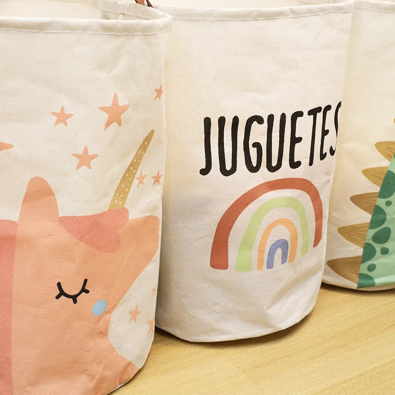 Three white fabric storage baskets featuring colorful cartoon unicorn and rainbow prints.
