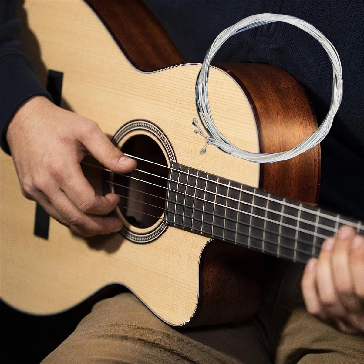 A person plays a light-colored classical guitar with silver-plated nylon strings.