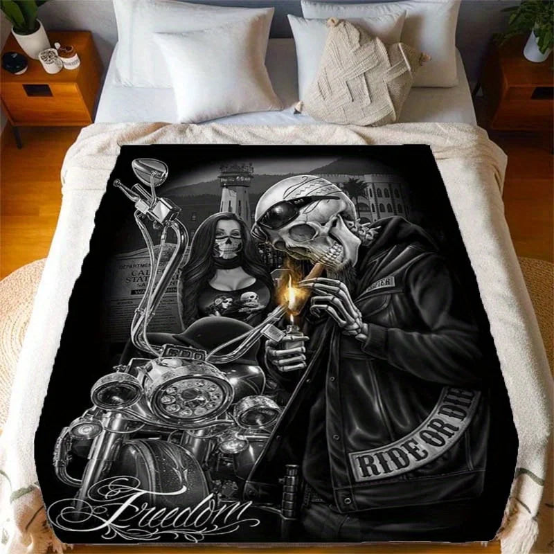 A black and white print featuring a skull and biker imagery on a flannel throw blanket.
