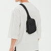 A black 2-in-1 convertible waist and crossbody sling bag worn on a white t-shirt.