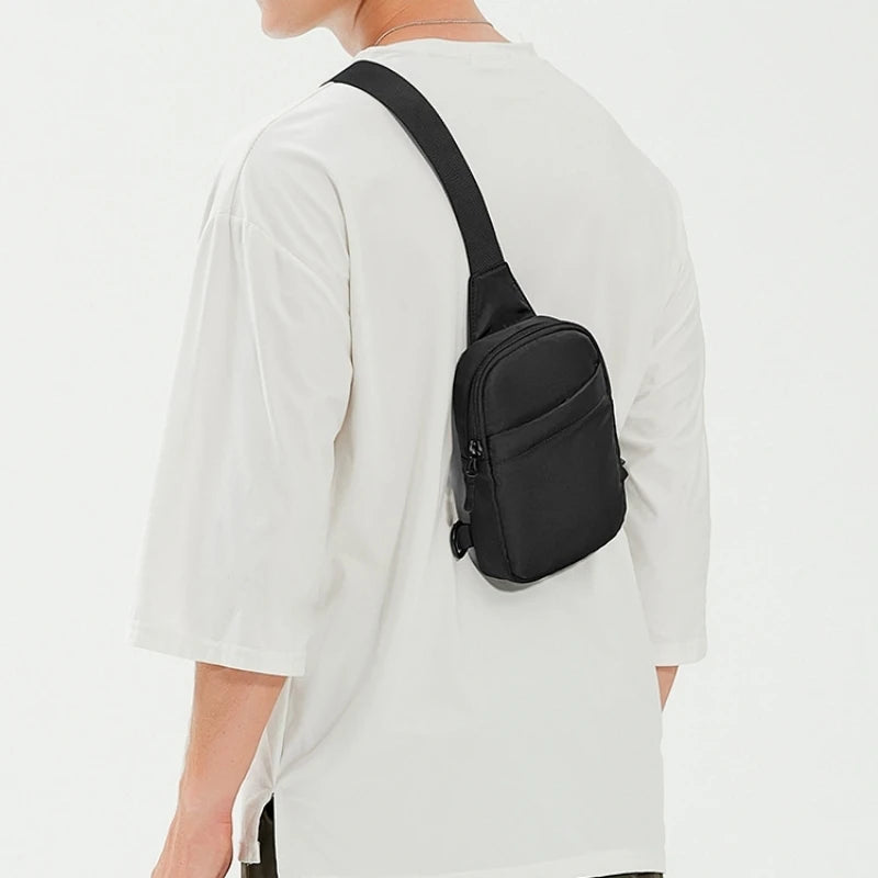 A black 2-in-1 convertible waist and crossbody sling bag worn on a white t-shirt.