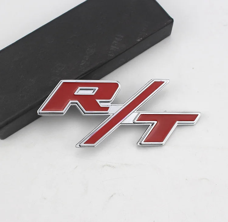 A silver and red metal emblem featuring the SRT logo on a black surface.