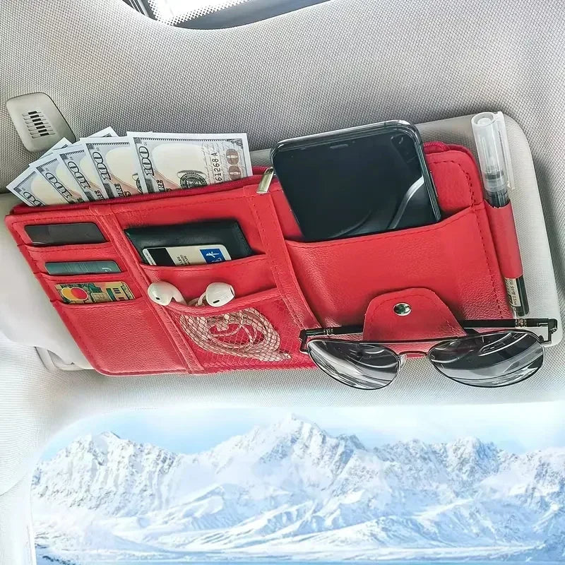 A red car sun visor organizer holding a smartphone, cards, and cash, placed on a white surface.