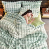 A light mint green fluffy bedding set featuring a duvet, pillows, and a matching throw blanket.