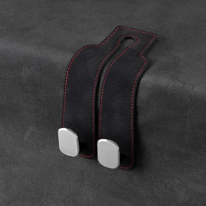 Black car headrest storage hook with a soft suede finish and red stitching