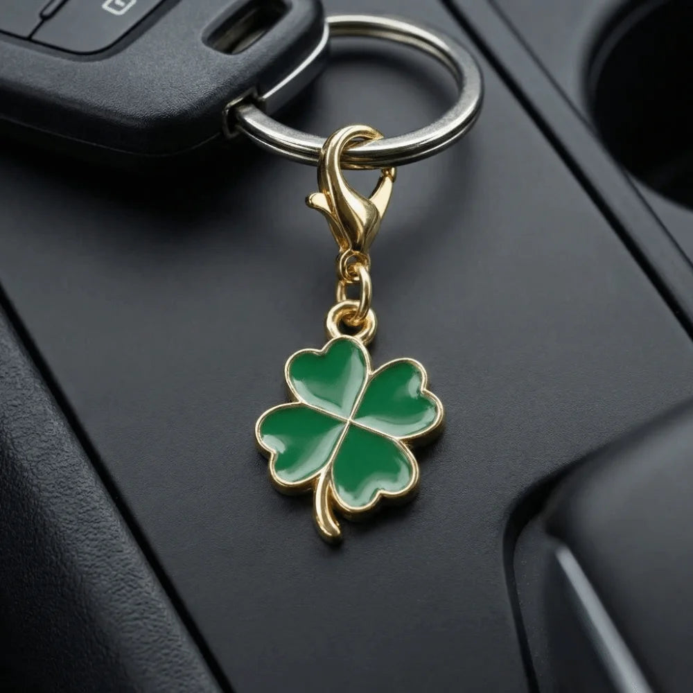 A gold-toned four-leaf clover charm attached to a keychain ring, resting on a black surface.