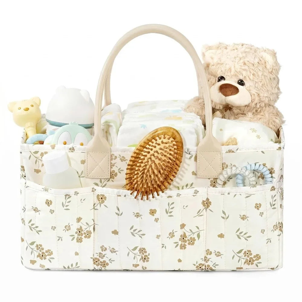 A beige floral diaper organizer bag with multiple compartments, featuring a teddy bear plush toy.