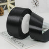 A roll of black satin ribbon used for gift wrapping or DIY crafts, shown on a white surface.