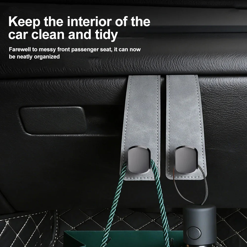 A close-up of a car seat back hook with a suede finish hanging from the interior of a car, designed for organizing bags and a