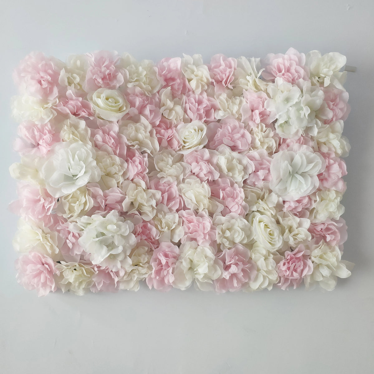 A wall panel covered in pink and white silk rose flowers for weddings and events.