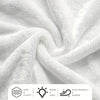 Nahaufnahme einer weißen, flauschigen Strickdecke, weich drapiert und gefaltet.