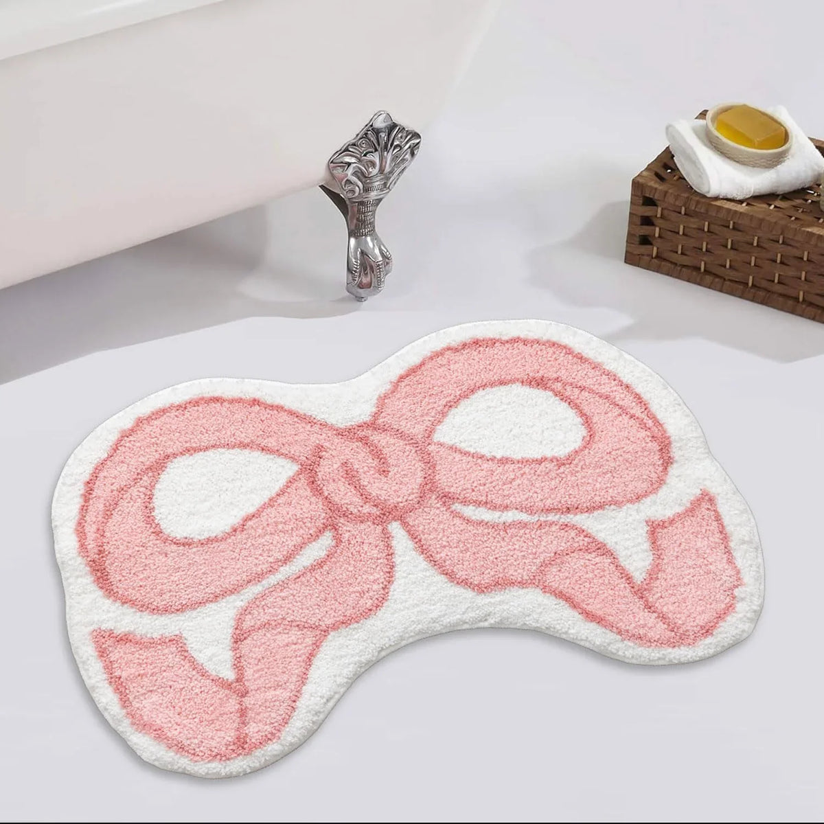 A pink, bow-shaped absorbent non-slip doormat with a decorative silver handle is shown on a white surface.
