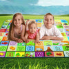 Three children sitting on a colorful soft foam baby play mat outdoors