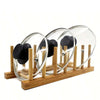 A wooden bamboo dish drying rack holding several clear glass bowls with black lids.