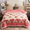 A pink and cream weighted plush blanket with floral embroidery is displayed on a bed.