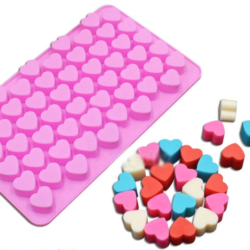 A pink silicone mold tray filled with small pink heart shapes and loose heart molds in various colors.
