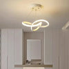 A modern pendant light fixture with a curved, ring-shaped design hangs from the ceiling above a vanity area.