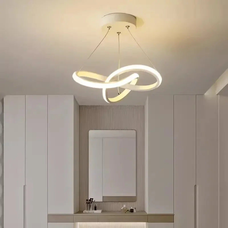 A modern pendant light fixture with a curved, ring-shaped design hangs from the ceiling above a vanity area.
