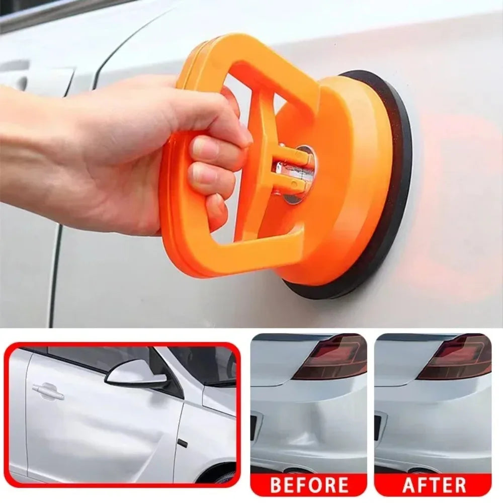 A hand is using an orange heavy-duty suction cup dent puller to lift a car body panel.