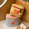 A yellow insulated lunch bag with a checkered pattern and a heart design is shown next to a pink lunch box.