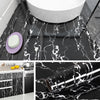 A close-up view of black marble contact paper rolled out on a dark surface, showcasing its marbled pattern.