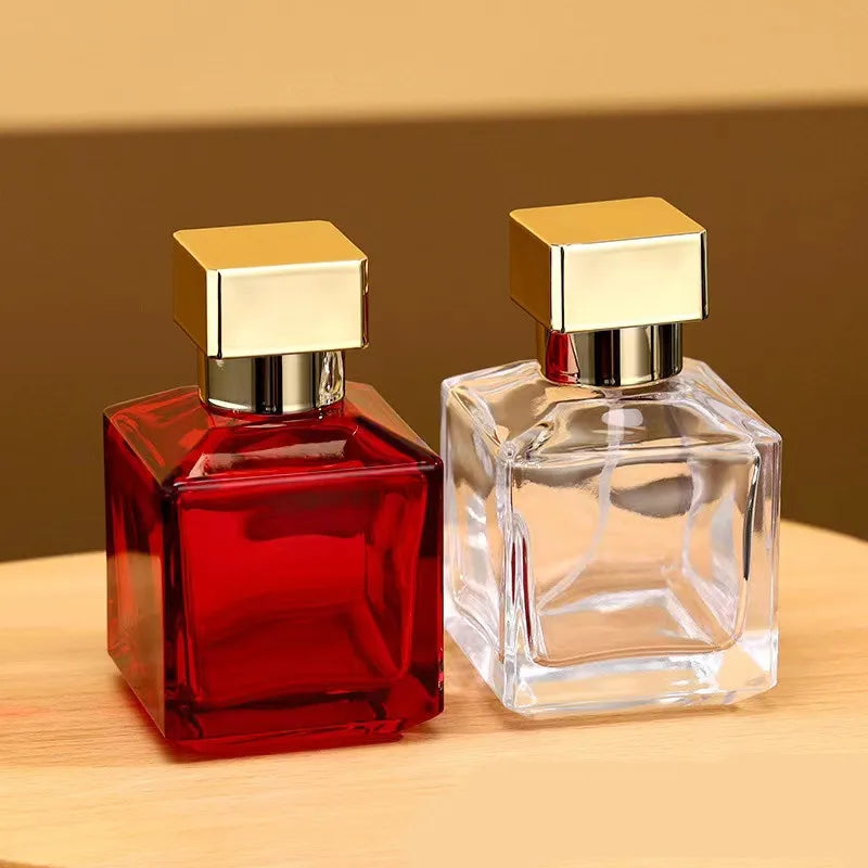 A clear glass perfume bottle with a gold sprayer cap and a red liquid, displayed on a wooden surface.