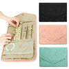 A foldable waterproof jewelry roll in pink and beige with various jewelry pieces displayed inside.