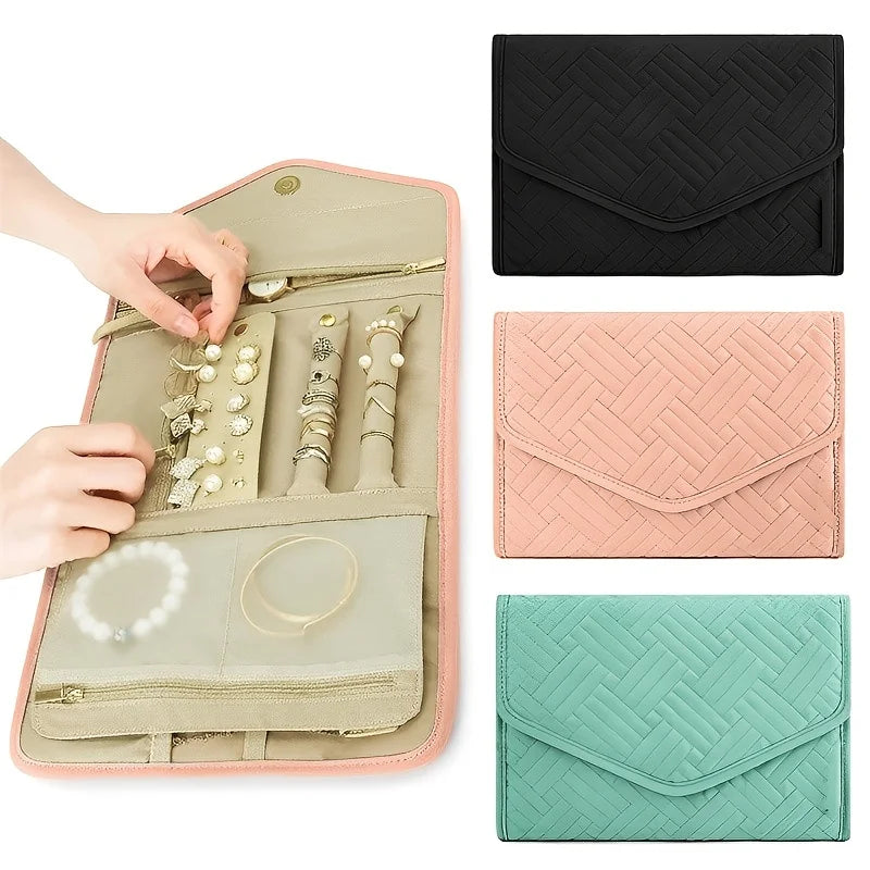 A foldable waterproof jewelry roll in pink and beige with various jewelry pieces displayed inside.