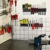 A wall mounted tool storage rack displaying various red and yellow hand tools for professional use.