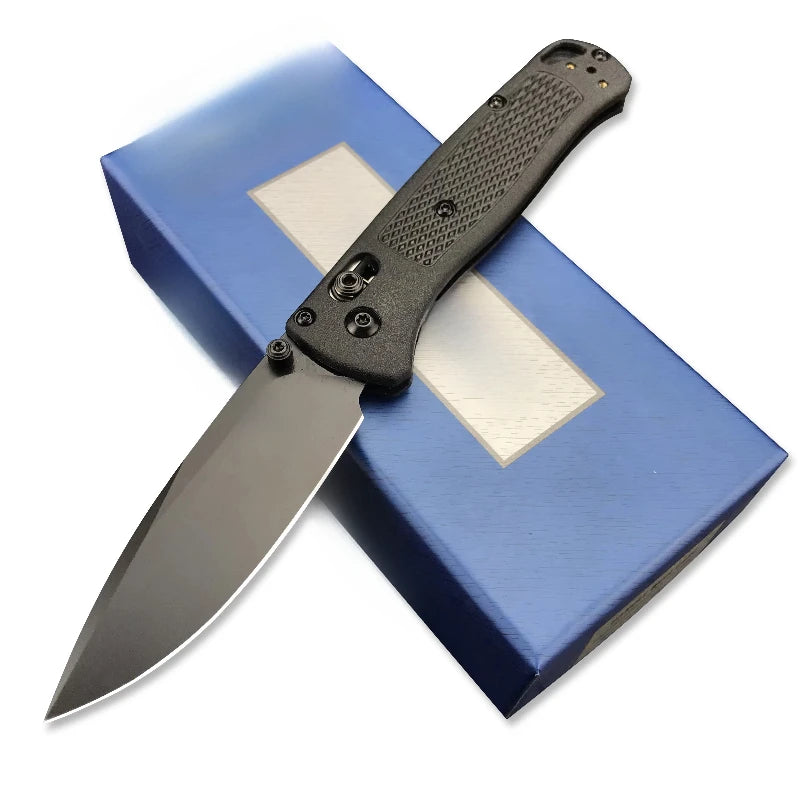 A compact folding knife with a black handle and stainless steel blade rests on a blue box.