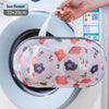 A white mesh laundry bag with a floral pattern is being placed inside a washing machine drum.