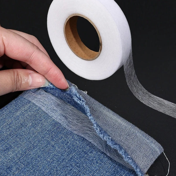 Eine Hand zieht ein Stück Denim-Stoff und zeigt den Rand, an dem strapazierfähiges doppelseitiges Zwischenfutterklebeband auf