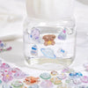 A glass bottle filled with liquid and various 3D jelly stickers of cute cartoon animals and a ghost rabbit