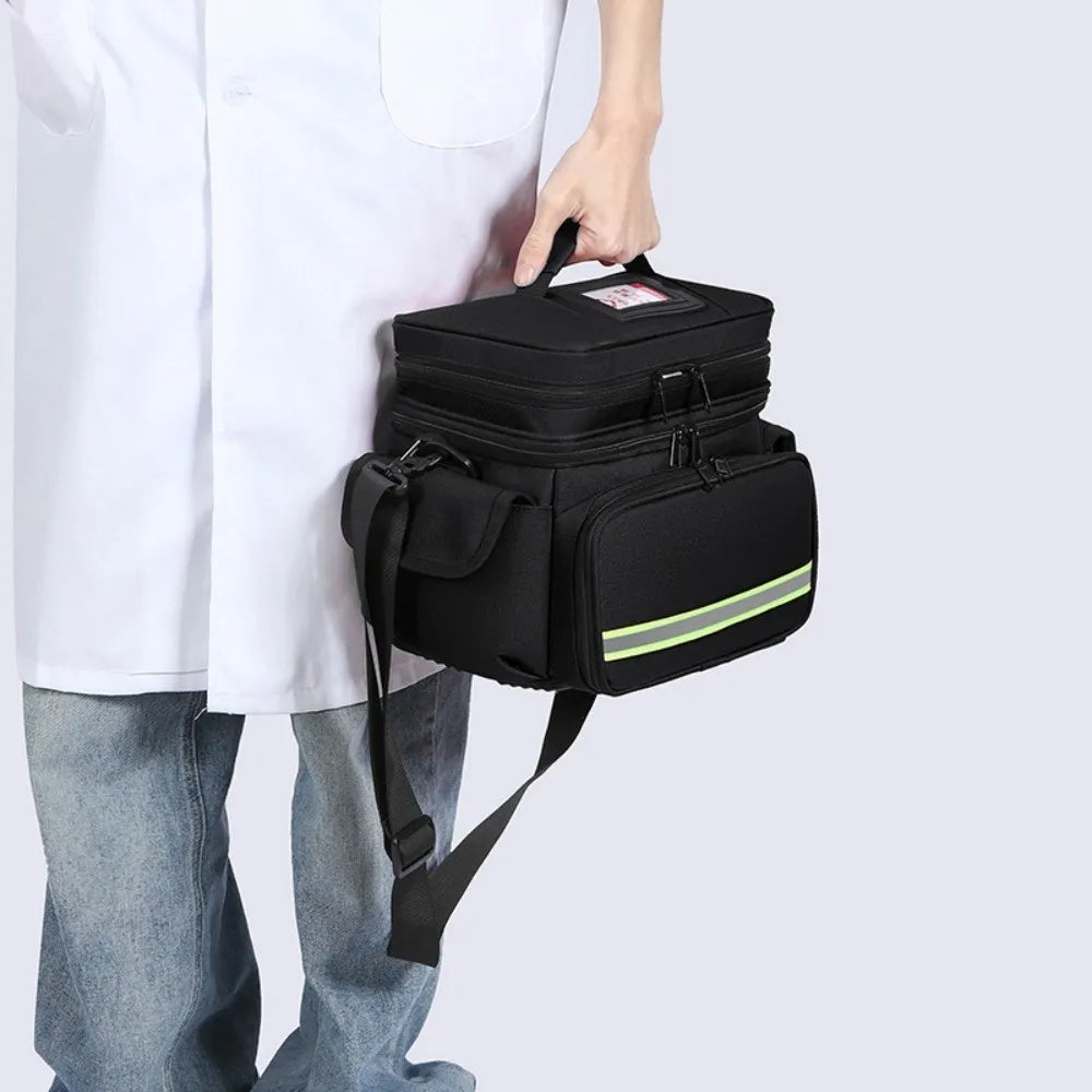 A person holds a black waterproof double-layer trauma and first aid bag for emergency medical supplies.