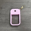 A pink silicone protective case for a hand sanitizer spray attached to a metal keyring.