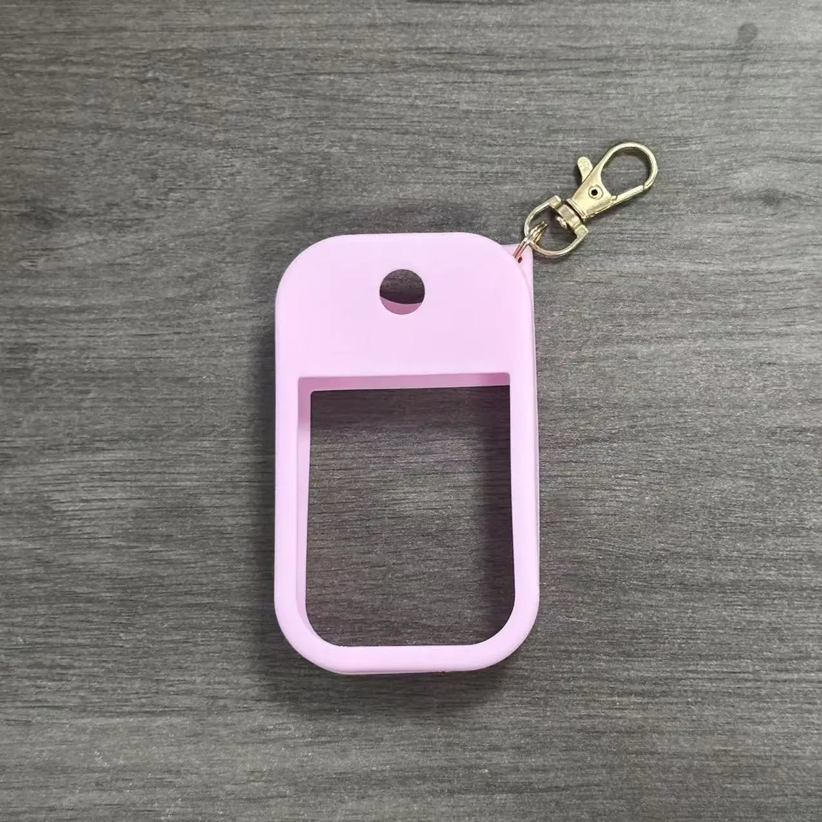 A pink silicone protective case for a hand sanitizer spray attached to a metal keyring.