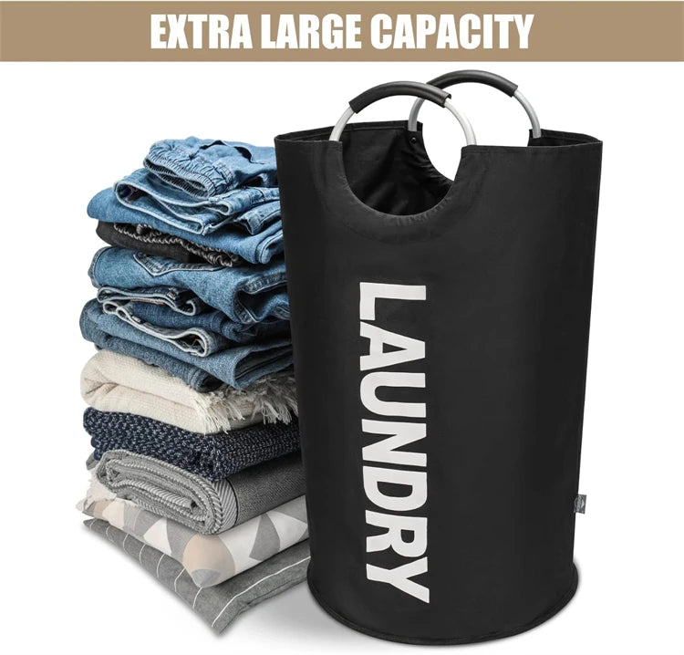 A black collapsible laundry basket with a handle is shown next to folded blue and gray clothes.