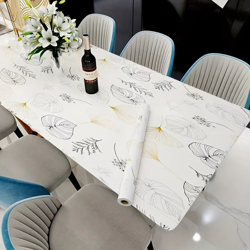 A white dining table set with gray chairs and a white tablecloth featuring a botanical pattern.