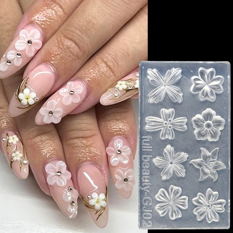 A hand displays long, pale pink nails decorated with delicate white floral silicone nail art molds.