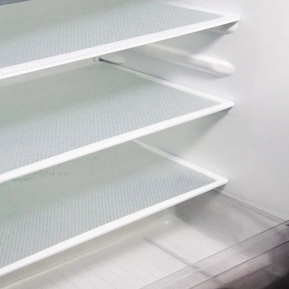 A close-up view of a white, perforated refrigerator liner mat with multiple shelves installed inside a cabinet.