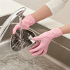 A hand wearing a pink disposable nitrile glove is using a faucet to rinse a metal cleaning tool in a stainless steel sink.