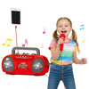 A young girl is singing into a microphone while a red karaoke machine with light effects is visible nearby.