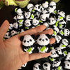 A hand holds a cluster of handmade crochet kitten keychains featuring cute panda and cartoon animal designs.