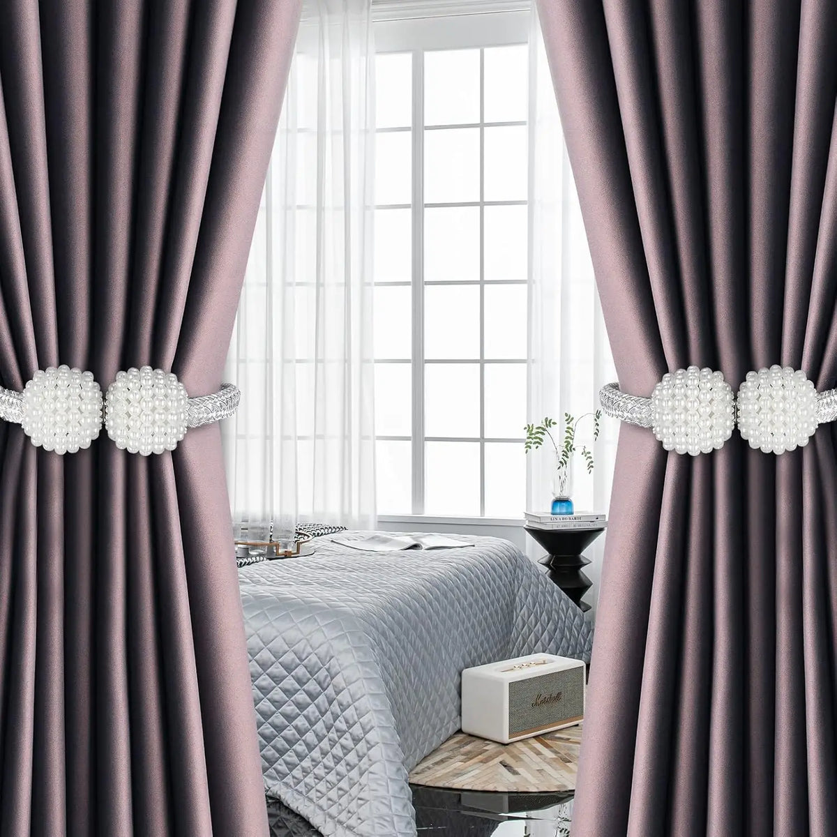 Close-up of pearl magnetic curtain tiebacks in silver and pink on a purple drape.
