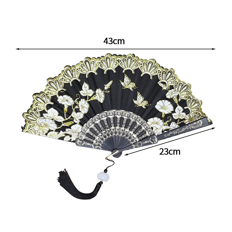 A black folding fan with a lace-trimmed golden edge and white floral patterns.