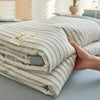 A stack of breathable summer quilts with a striped beige and gray pattern, shown from the side.