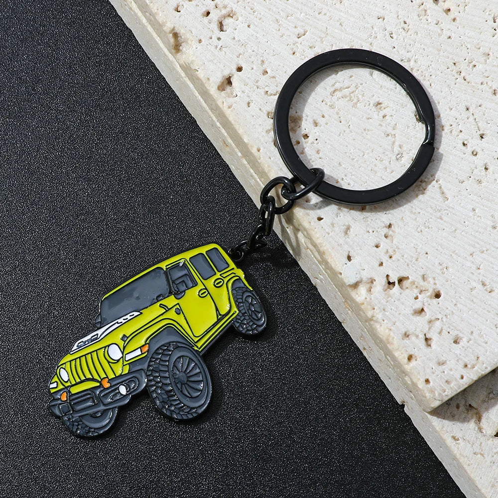A yellow Ford Bronco zinc alloy keychain attached to a black ring, resting on a light wooden surface.