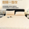 A close-up of a thick, ribbed, cream-colored knit fitted bed sheet with two fluffy pillows on a bed.